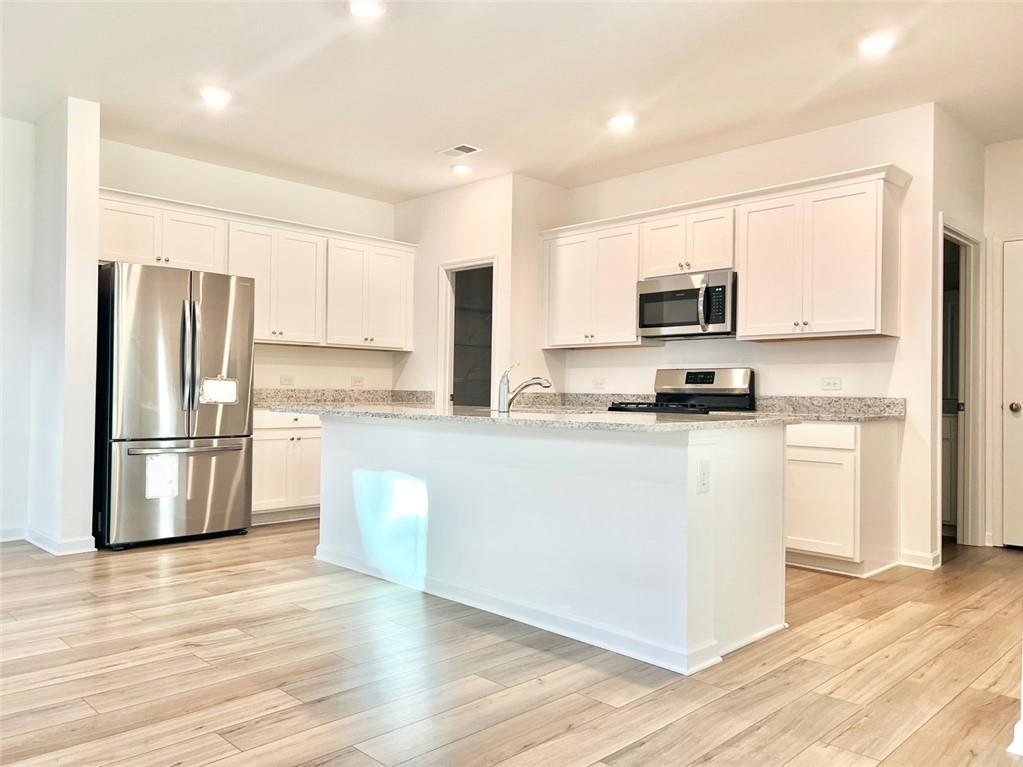 1529 Hay Patch Lane Loganville, GA 30052 - Photo 5 of 24 a kitchen with kitchen island a refrigerator and a stove top oven