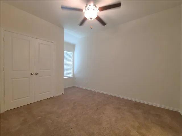 a view of an empty room and chandelier fan