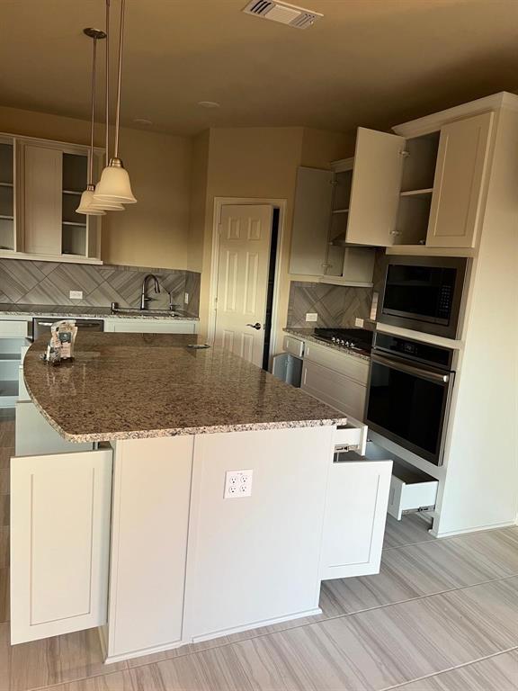 504 Christie Crossing Celina, TX 75009 - Photo 4 of 24 a kitchen with kitchen island granite countertop a stove and a sink