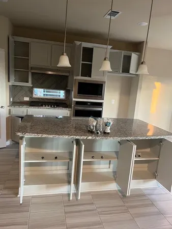 a kitchen with kitchen island granite countertop a oven and a view of living room