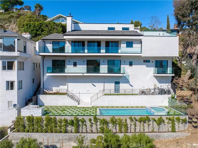 a view of a white building among the street with potted plants
