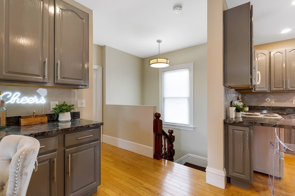 34 Warren Street, Unit 3 Stoneham, MA 02180 - Photo 13 of 34 a kitchen with granite countertop wooden floors and stainless steel appliances