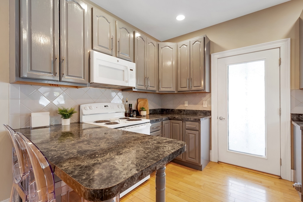 34 Warren Street, Unit 3 Stoneham, MA 02180 - Photo 8 of 34 a kitchen with stainless steel appliances granite countertop a stove a sink and a microwave