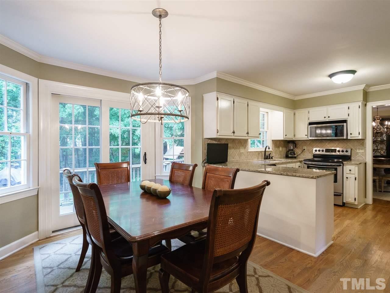 7405 Glendower Road Raleigh, NC 27613 - Photo 12 of 25 a view of a dining room and livingroom with furniture wooden floor a chandelier