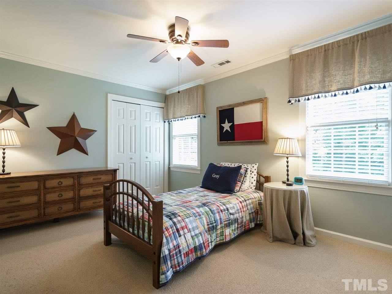 7405 Glendower Road Raleigh, NC 27613 - Photo 16 of 25 a bedroom with a bed a chandelier and a dresser