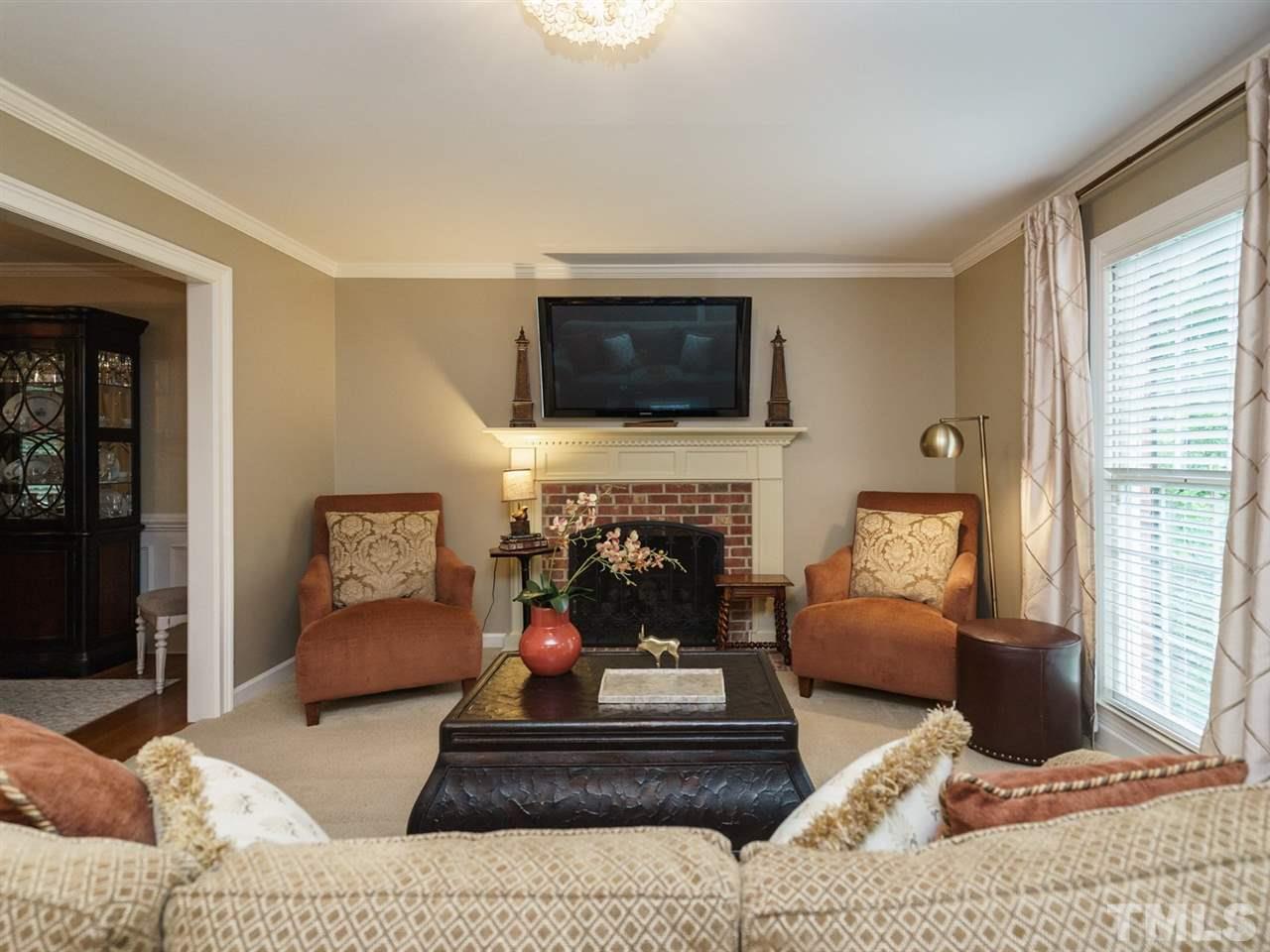 7405 Glendower Road Raleigh, NC 27613 - Photo 4 of 25 a living room with furniture a fireplace and a flat screen tv
