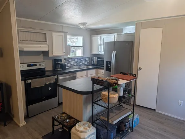 a kitchen with stainless steel appliances granite countertop a stove a refrigerator and a dining table