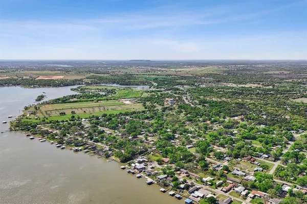 an aerial view of a houses with a yard and ocean view