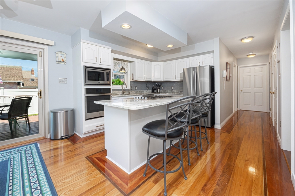 59 J Street Hull, MA 02045 - Photo 13 of 35 a kitchen with stainless steel appliances granite countertop a refrigerator a stove top oven a sink dishwasher and white cabinets with wooden floor