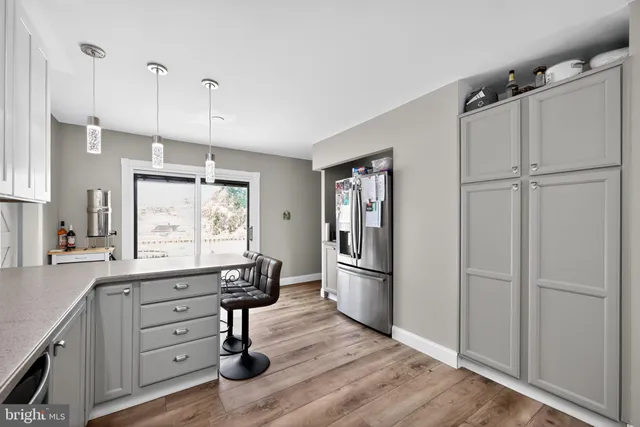 a kitchen with granite countertop a refrigerator a stove and white cabinets with wooden floor