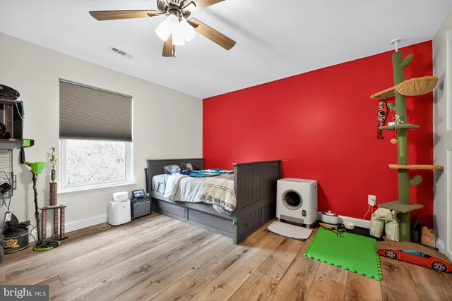a spacious bedroom with a bed and a flat tv screen on dresser