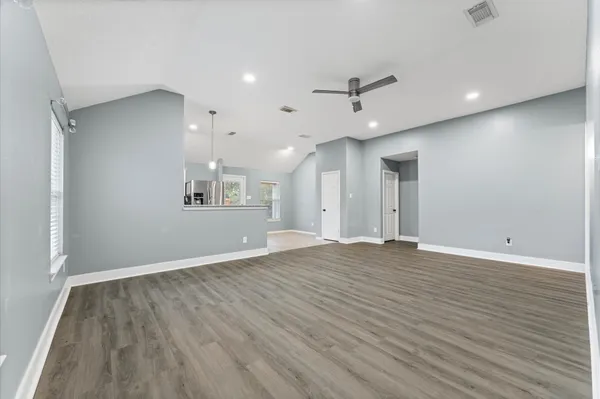 an empty room with wooden floor and windows