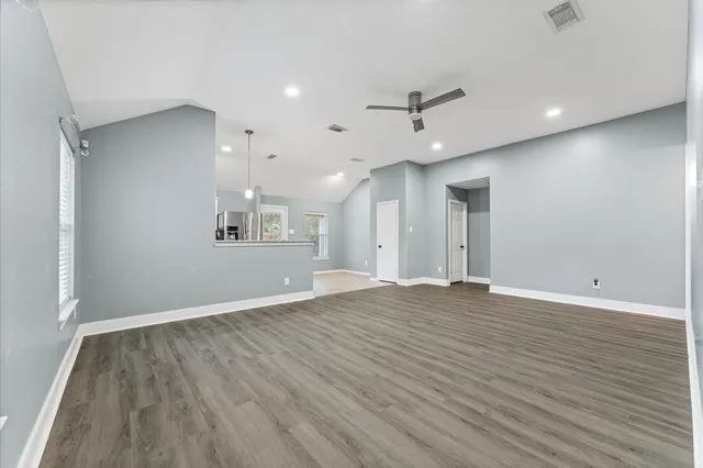 an empty room with wooden floor and windows