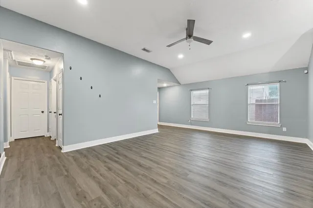 an empty room with wooden floor and windows