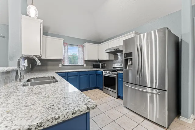 a kitchen with granite countertop a refrigerator and a sink