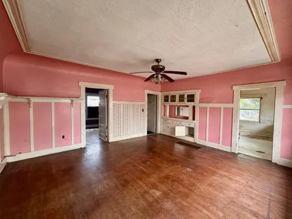 a view of an empty room with window and wooden floor