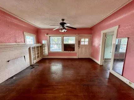 a view of an empty room with window and wooden floor