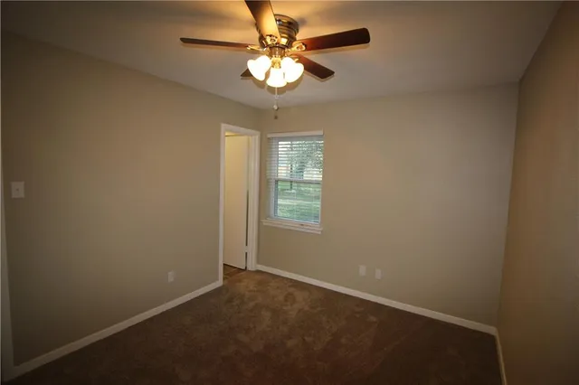 an empty room with a chandelier fan and windows
