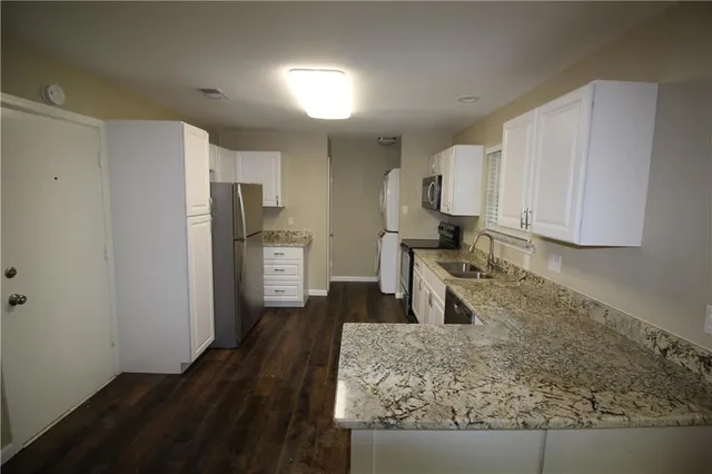 a kitchen with stainless steel appliances granite countertop a refrigerator a stove and a sink