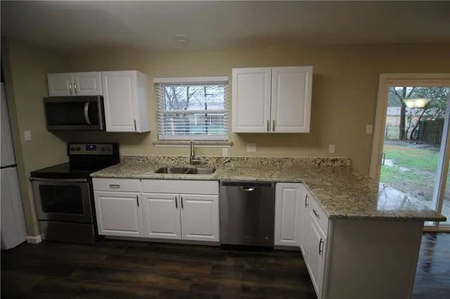a kitchen with granite countertop a sink and a stove top oven