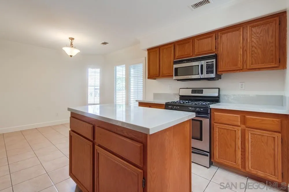 3924 Tortuga Cove Oceanside, CA 92058 - Photo 12 of 42 a kitchen with stainless steel appliances granite countertop a stove a sink and a microwave