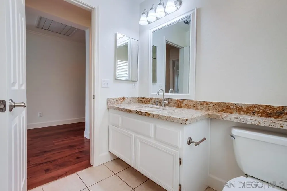 3924 Tortuga Cove Oceanside, CA 92058 - Photo 36 of 42 a bathroom with a granite countertop sink a toilet and a mirror