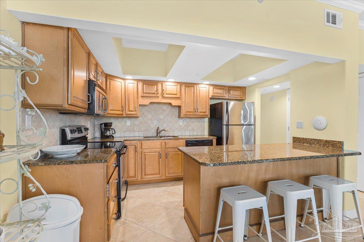 16284 Perdido Key Drive, Unit 112 Perdido Key, FL 32507 - Photo 19 of 37 a kitchen with stainless steel appliances granite countertop a sink a stove a refrigerator cabinets and chairs