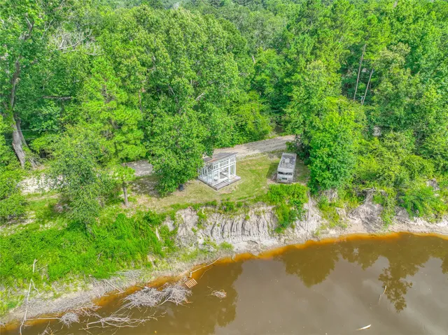 a view of a street with a bench under large trees