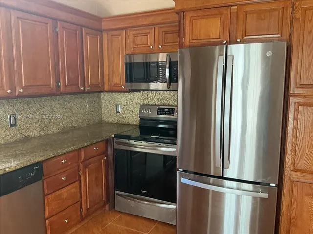 a kitchen with granite countertop stainless steel appliances and wooden cabinets