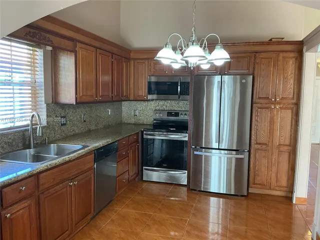 a kitchen with granite countertop stainless steel appliances a sink cabinets and a window