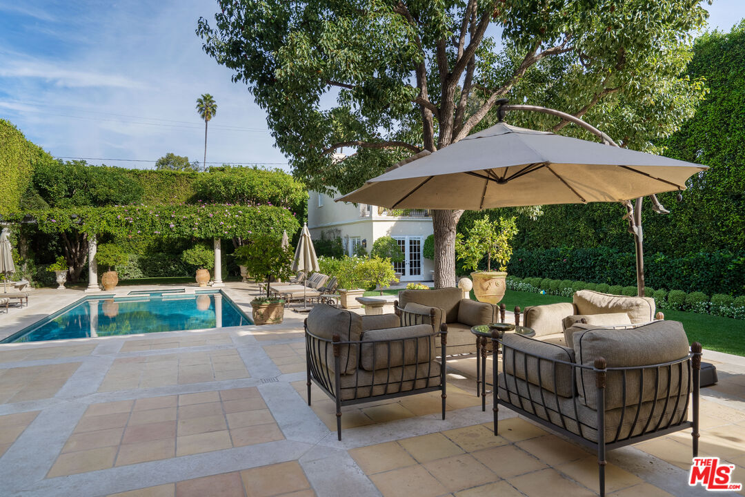 722 North Elm Drive Beverly Hills, CA 90210 - Photo 34 of 51 a view of a patio with couches table and chairs under an umbrella
