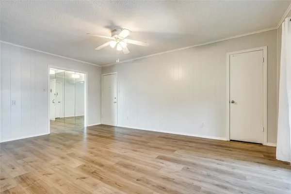 an empty room with wooden floor and fan