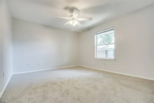 an empty room with a chandelier fan and windows