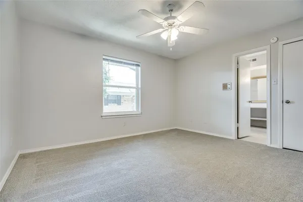 an empty room with a window and a ceiling fan