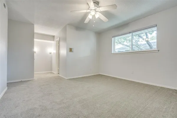 an empty room with a window and a fan