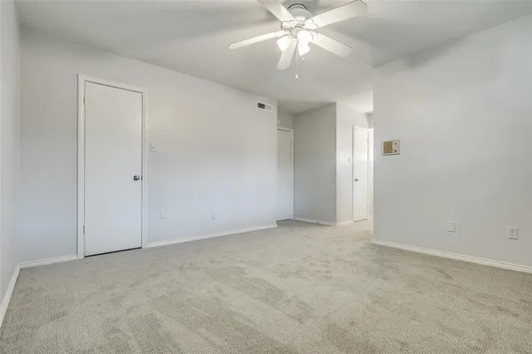 an empty room with a chandelier fan and closet area