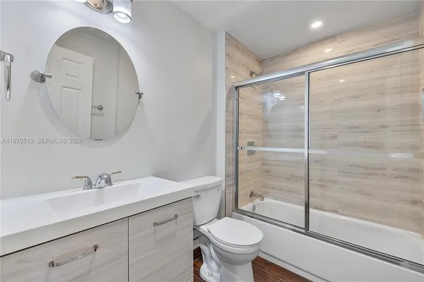 a bathroom with a shower sink vanity mirror and toilet