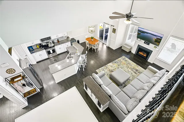 a kitchen with stainless steel appliances kitchen island granite countertop a refrigerator a stove a sink a dining table and chairs with wooden floor