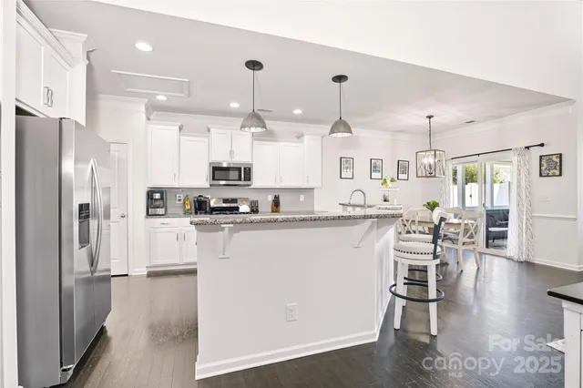 a kitchen with stainless steel appliances a table chairs refrigerator and microwave