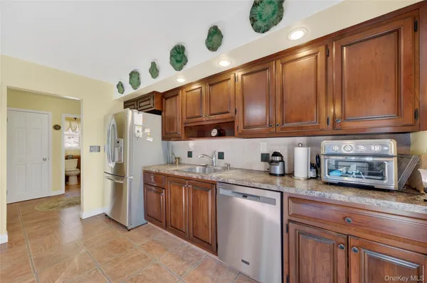 a kitchen with stainless steel appliances granite countertop a refrigerator a sink dishwasher and wooden cabinets with wooden floor