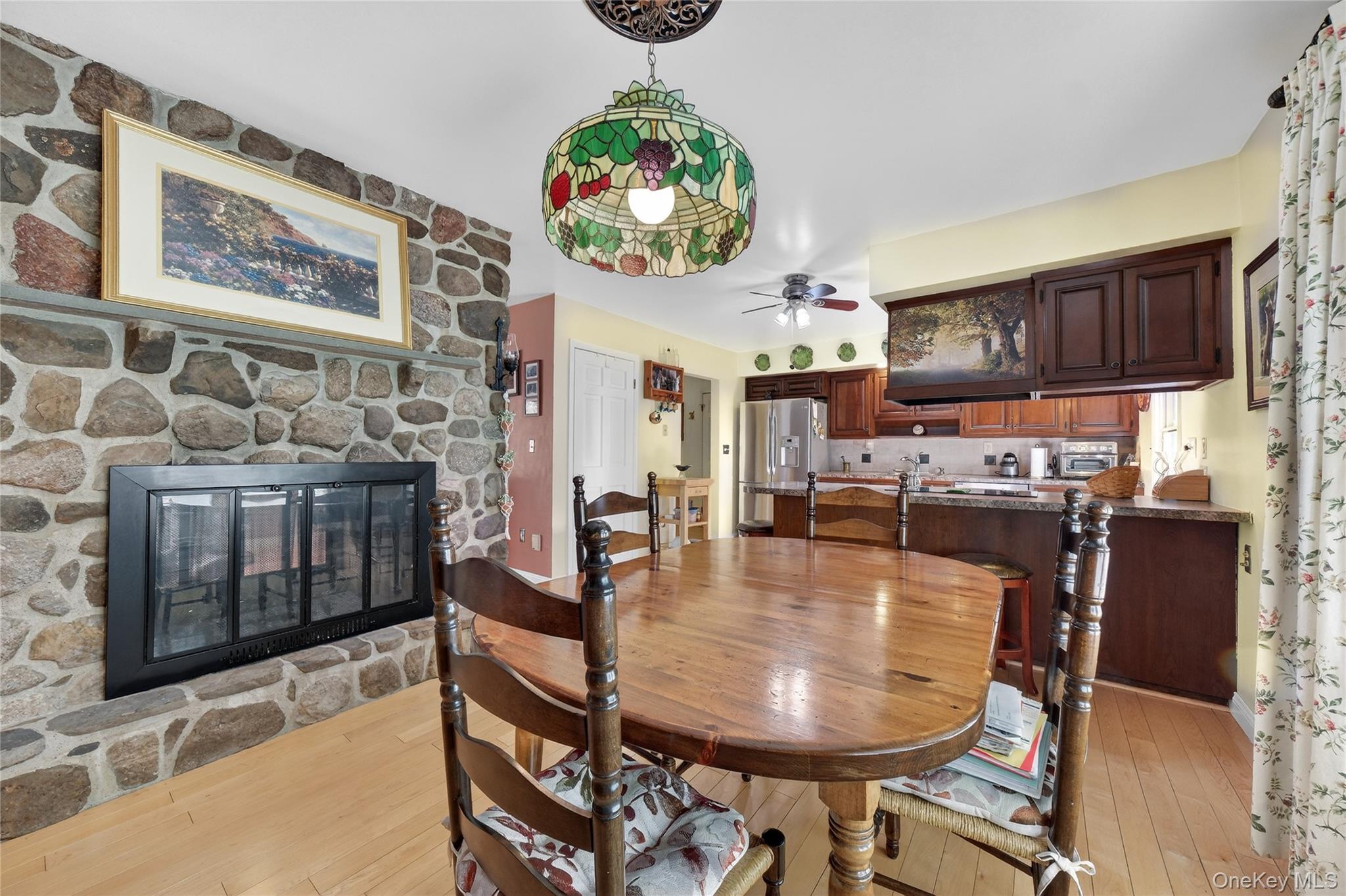 123 Fleury Road Pine Bush, NY 12566 - Photo 19 of 46 Dining room with a stone fireplace, light wood-type flooring, and a ceiling fan