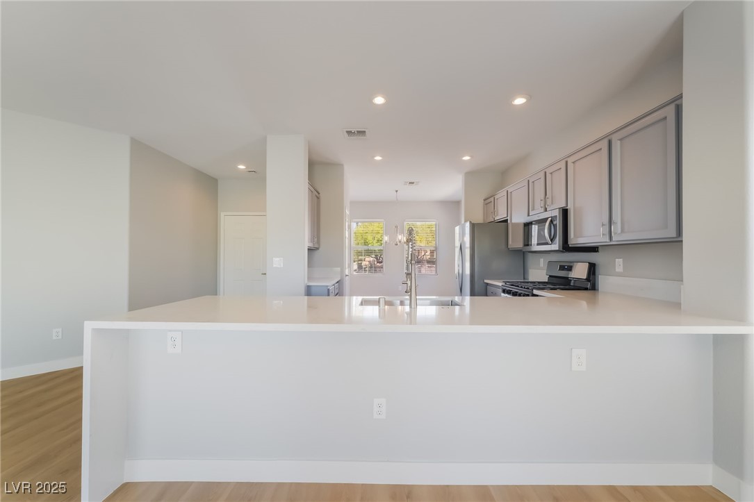 1442 Fieldbrook Street Henderson, NV 89052 - Photo 16 of 36 Kitchen featuring gray cabinetry, recessed lighting, appliances with stainless steel finishes, light wood-style floors, and a peninsula