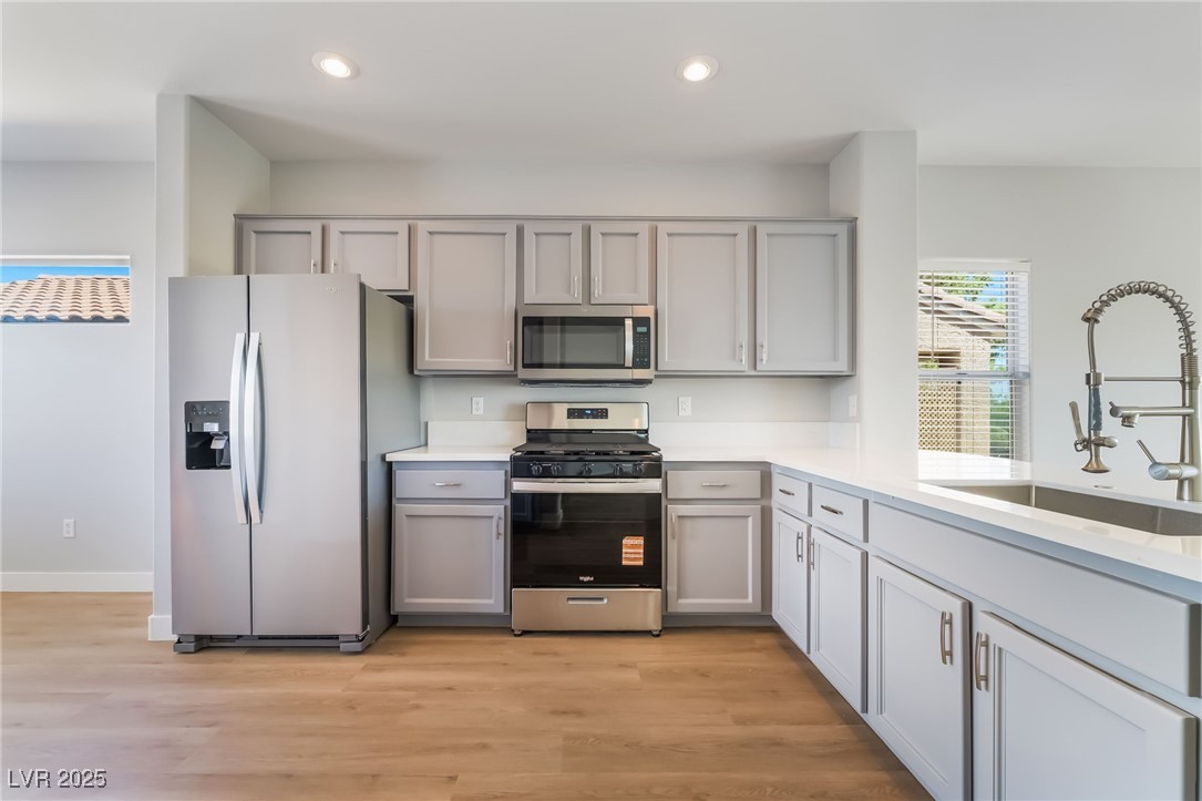1442 Fieldbrook Street Henderson, NV 89052 - Photo 17 of 36 Kitchen with appliances with stainless steel finishes, light wood-style floors, recessed lighting, light stone countertops, and gray cabinetry