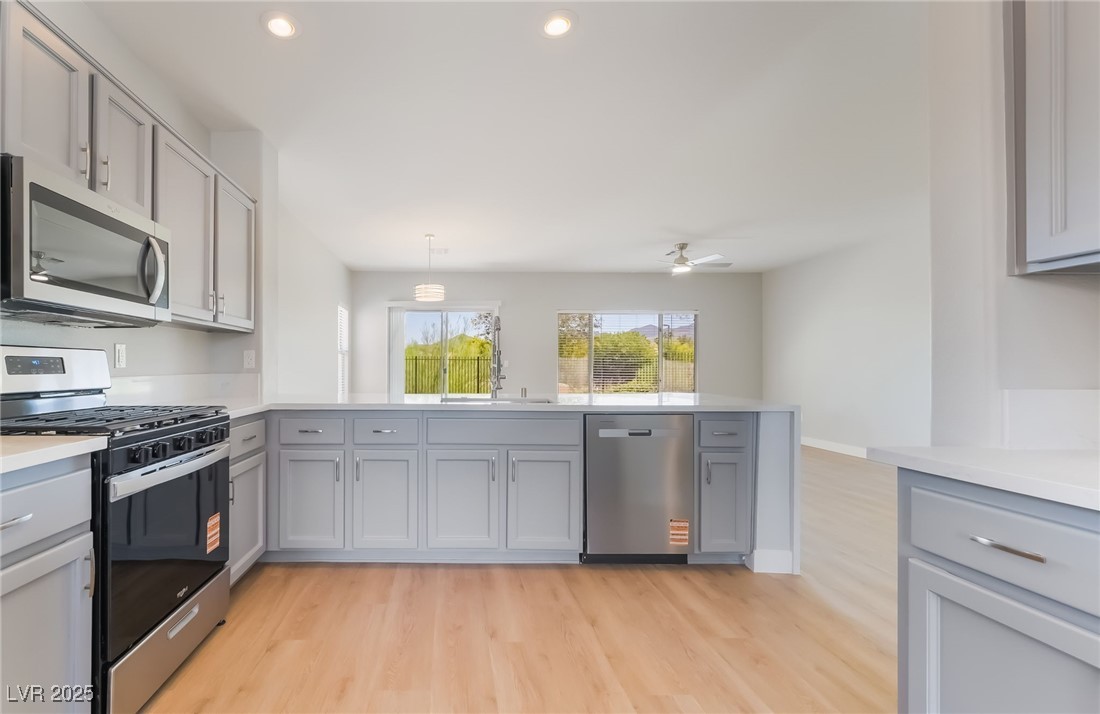 1442 Fieldbrook Street Henderson, NV 89052 - Photo 18 of 36 Kitchen with appliances with stainless steel finishes, light wood-type flooring, a peninsula, gray cabinetry, and recessed lighting
