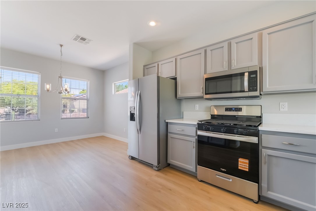 1442 Fieldbrook Street Henderson, NV 89052 - Photo 19 of 36 Kitchen with gray cabinetry, appliances with stainless steel finishes, light countertops, a chandelier, and pendant lighting
