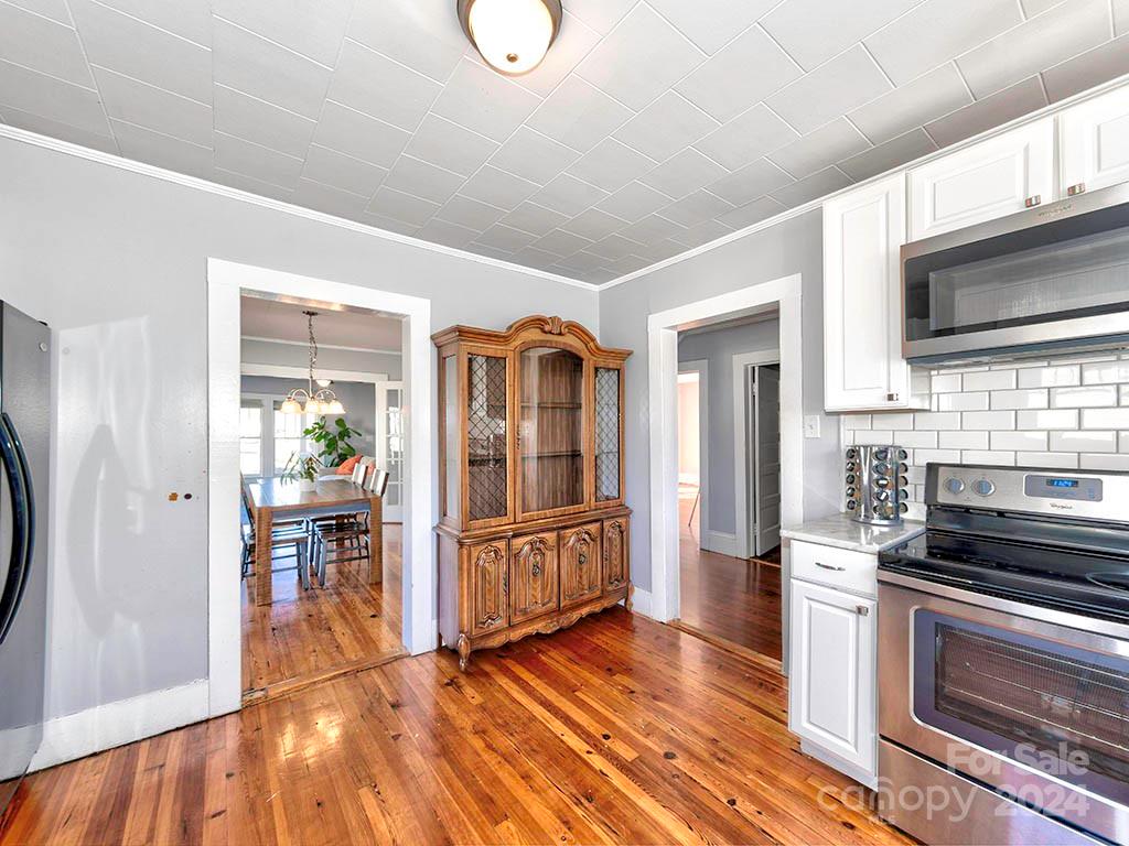 508 South Main Street Troutman, NC 28166 - Photo 13 of 38 a kitchen with granite countertop a stove top oven a sink dishwasher a dining table and chairs with wooden floor