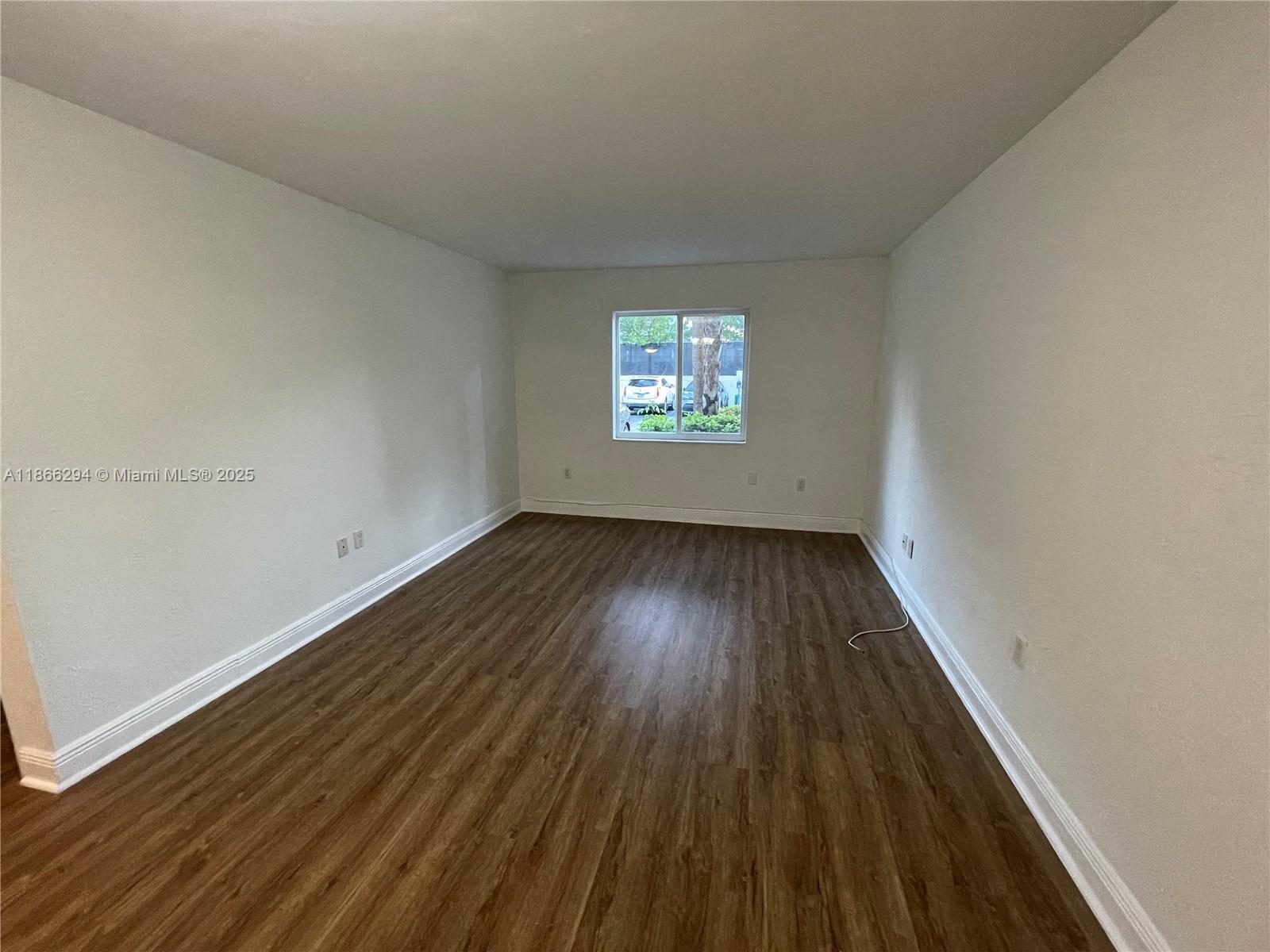 8605 Southwest 68th Court, Unit 1 Pinecrest, FL 33156 - Photo 5 of 20 a view of an empty room with wooden floor and window