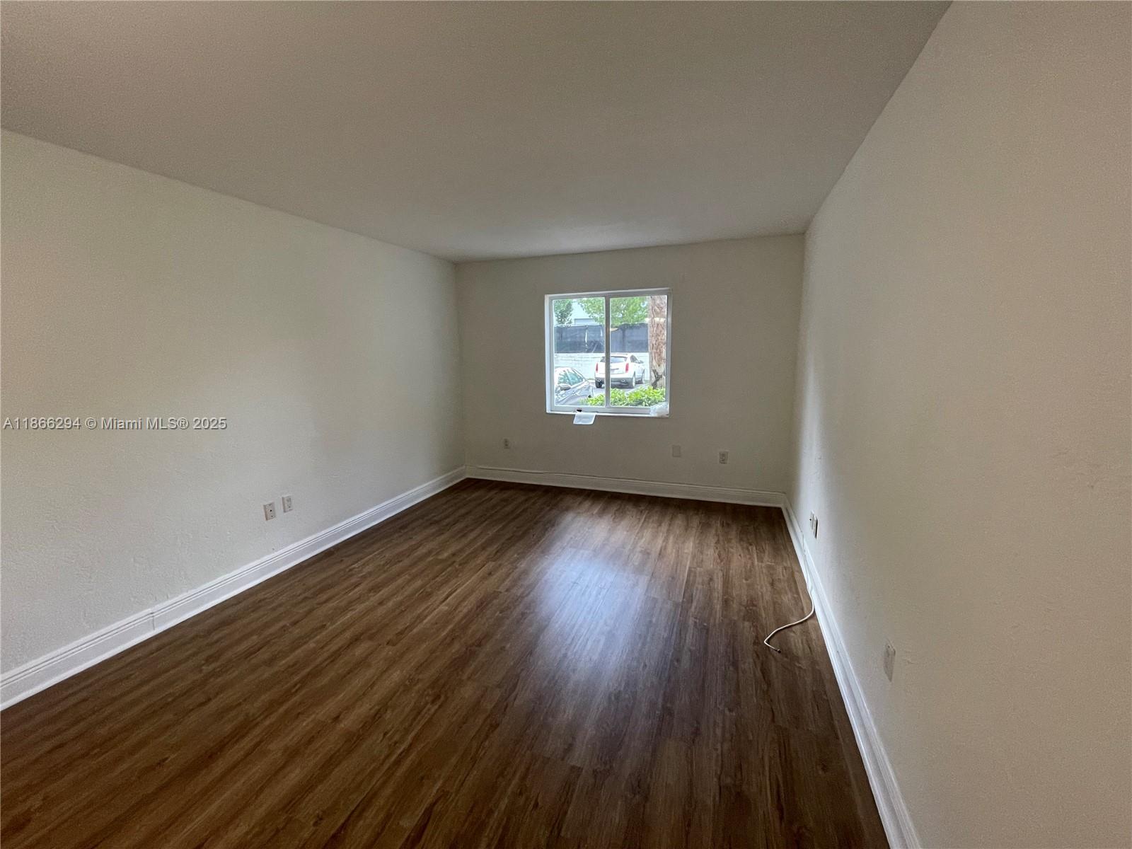 8605 Southwest 68th Court, Unit 1 Pinecrest, FL 33156 - Photo 9 of 20 an empty room with wooden floor and windows