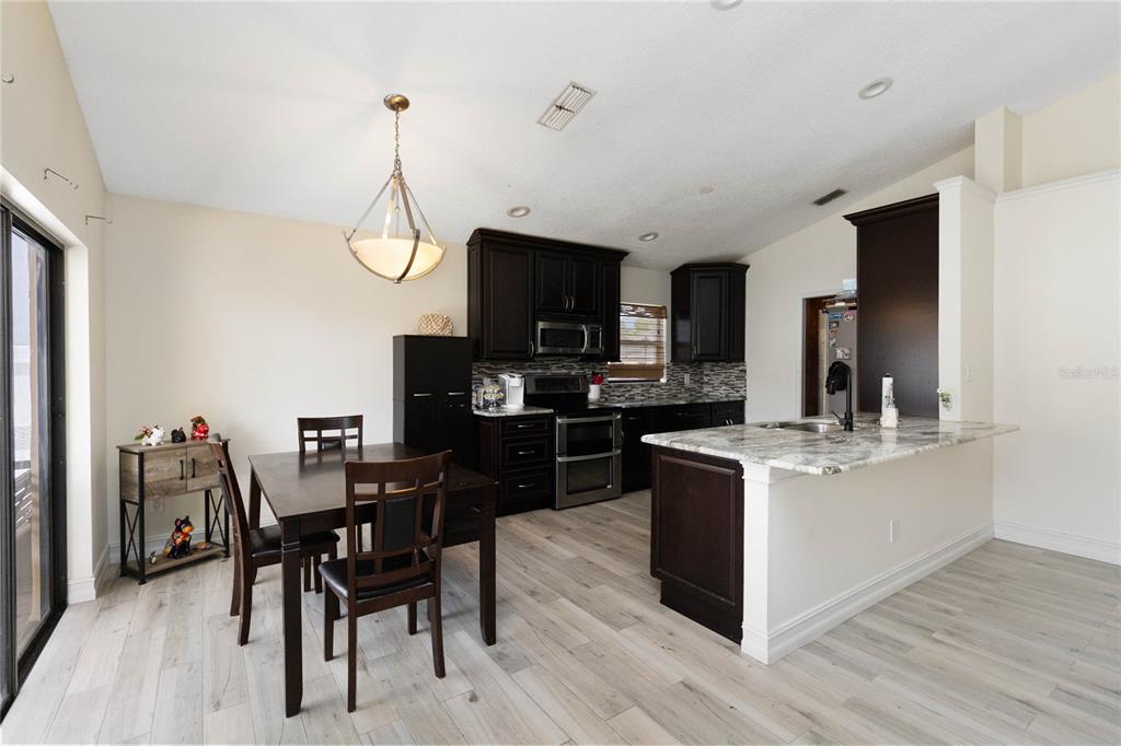 1647 Riveredge Road Oviedo, FL 32766 - Photo 8 of 28 a kitchen with stainless steel appliances granite countertop a stove top oven a sink dishwasher a dining table and chairs with wooden floor