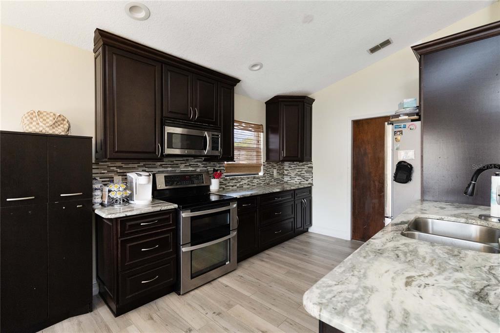 1647 Riveredge Road Oviedo, FL 32766 - Photo 10 of 28 a kitchen with stainless steel appliances granite countertop a stove refrigerator and microwave